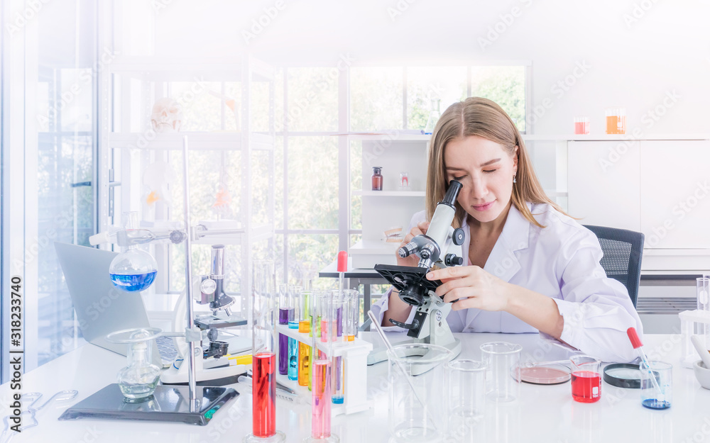 pretty scientist looking through a microscope in a chemical laboratory pretty scientist looking through a microscope in a chemical laboratory