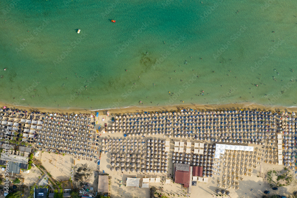 Aerial top view on the sandy beach. Umbrellas, sand and sea waves landscape.