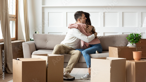Happy couple hug on couch excited to move together