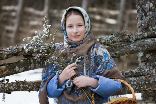 A young Orthodox girl in a Russian headscarf holds willow branches in her hands. The concept of spring and Easter.