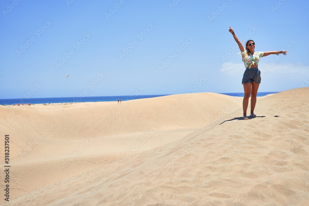Young beautiful girl on vacation wearing summer clothe smiling happy and confident. Standing with a smile on face and hands raised at beach