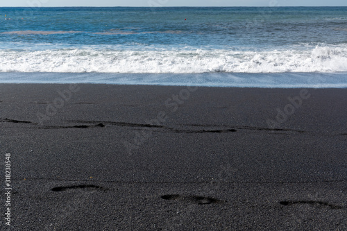 Footprints on black lava sand beach in Puerto Naos, La Palma, Canarian islands, Spain photo