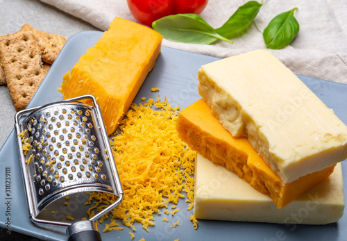 Cheese collection, matured and orange original British cheddar cheese in blocks and grated served on grey plate