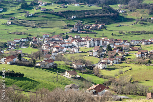 Idyllic view of a white houses village surrounded by green meadows. Berastegi, Basque Country, Spain. 