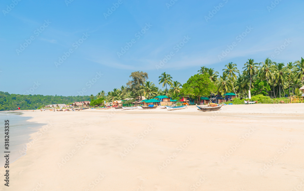 Beautiful beach view with fishing boat, yellow sand and blue ocean, Goa state in India