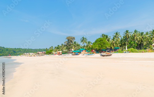 Beautiful beach view with fishing boat, yellow sand and blue ocean, Goa state in India