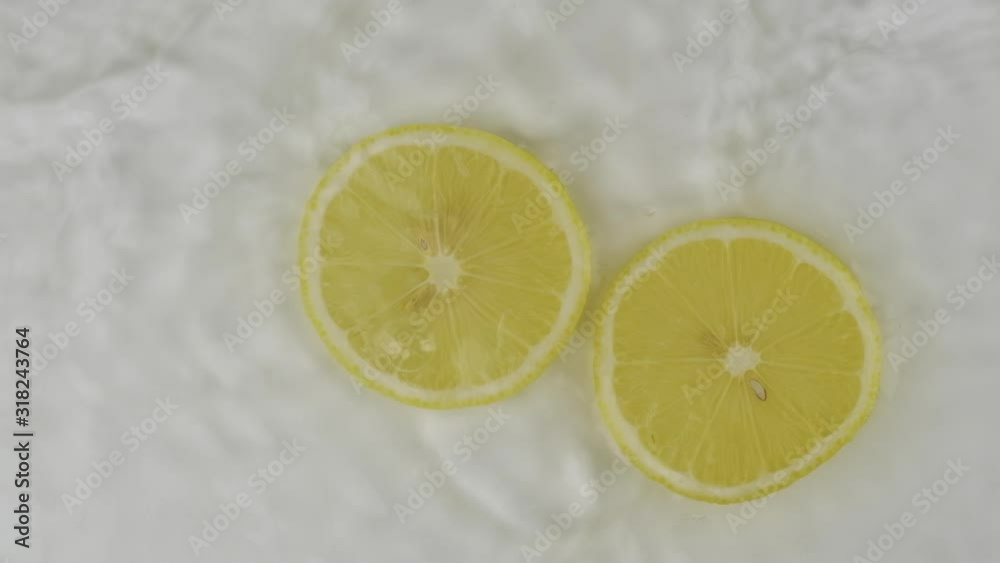Beautiful fall of two slices of lemon in white water. Slow motion. Top view. Beautiful fall of two slices of lemon in white water. Slow motion. Top view.