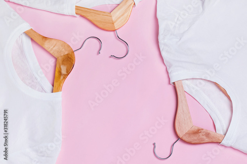 White T-Shirts on wooden hangers over pink background