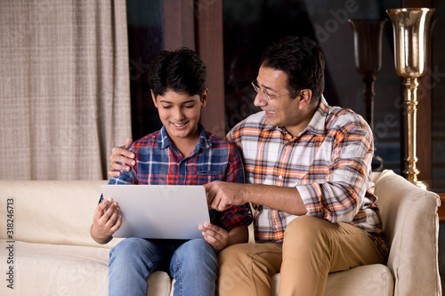 Father and son astonished on receiving good news using laptop