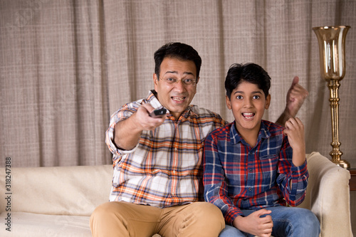 Enthusiastic father and son cheering while watching tv at home