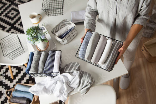 Spring cleaning of closet. Vertical tidying up storage. Neatly folded clothes in the metal black baskets for wardrobe. Nordic style.