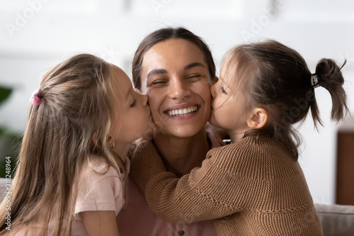 Fotografie Little girl kiss on cheeks smiling young mom