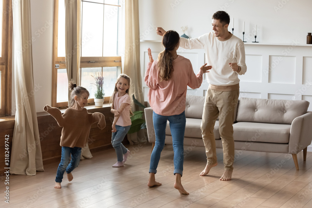 Fototapeta premium Happy family with little kids dancing in living room