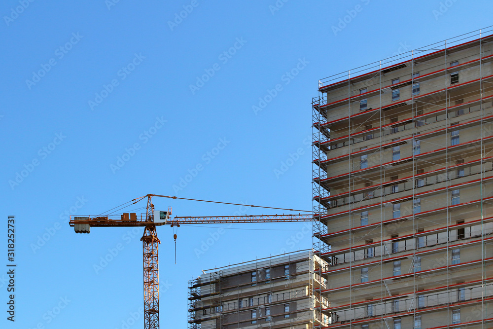 Construction of a high multi-storey building. Skyscraper furnished with metal scaffolding. Dangerous work at height. Modern architecture in the arrangement of the city. Urbanization of the environment Construction of a high multi-storey building. Skyscraper furnished with metal scaffolding. Dangerous work at height. Modern architecture in the arrangement of the city. Urbanization of the environment