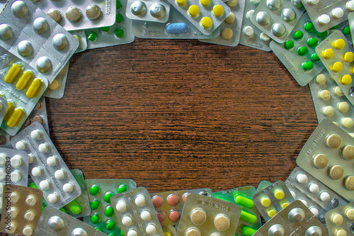 Frame, cadre made of pills spilling on brown background. Medicine concept of medicament treatment