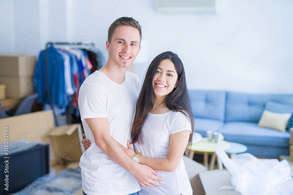 Young beautiful couple hugging at new home around cardboard boxes Young beautiful couple hugging at new home around cardboard boxes
