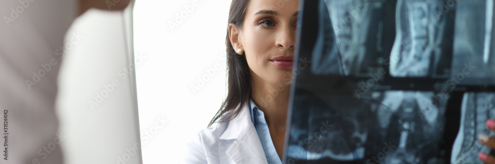 Portrait of serious surgeon looking carefully on spine x-ray in different projections. Cute doc discussing disease diagnosis with colleague. Healthcare concept Portrait of serious surgeon looking carefully on spine x-ray in different projections. Cute doc discussing disease diagnosis with colleague. Healthcare concept