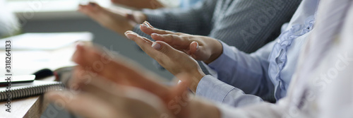 Close-up of business people hands. Man and woman sitting in office conference room and applauding on biz presentation of new project. Teamwork concept