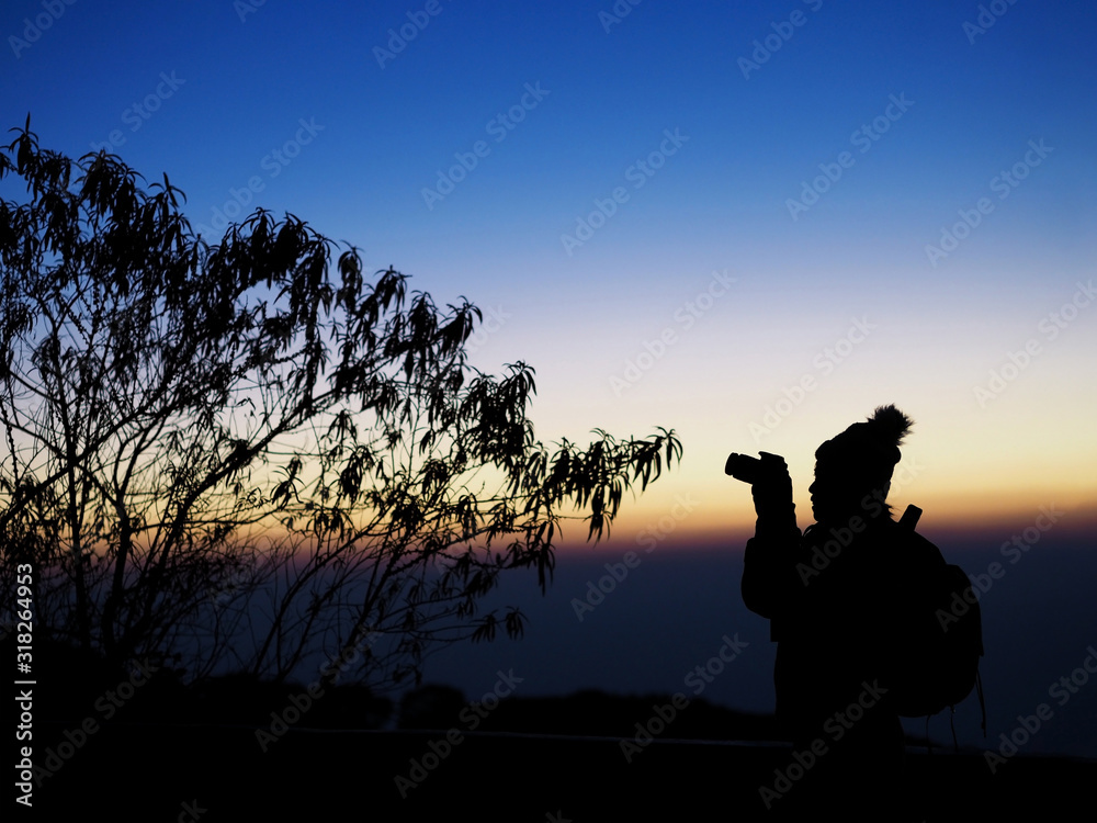 Silhouette of woman photographer at sunrise sky in winter.