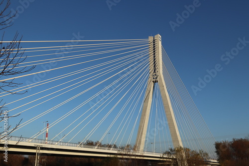 Rzeszow, Poland - 9 9 2018: Suspended road bridge across the Wislok River. Metal construction technological structure. Modern architecture. A white cross on a blue background is a symbol of the city