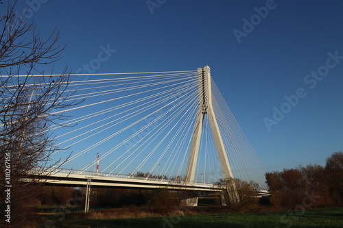 Rzeszow, Poland - 9 9 2018: Suspended road bridge across the Wislok River. Metal construction technological structure. Modern architecture. A white cross on a blue background is a symbol of the city