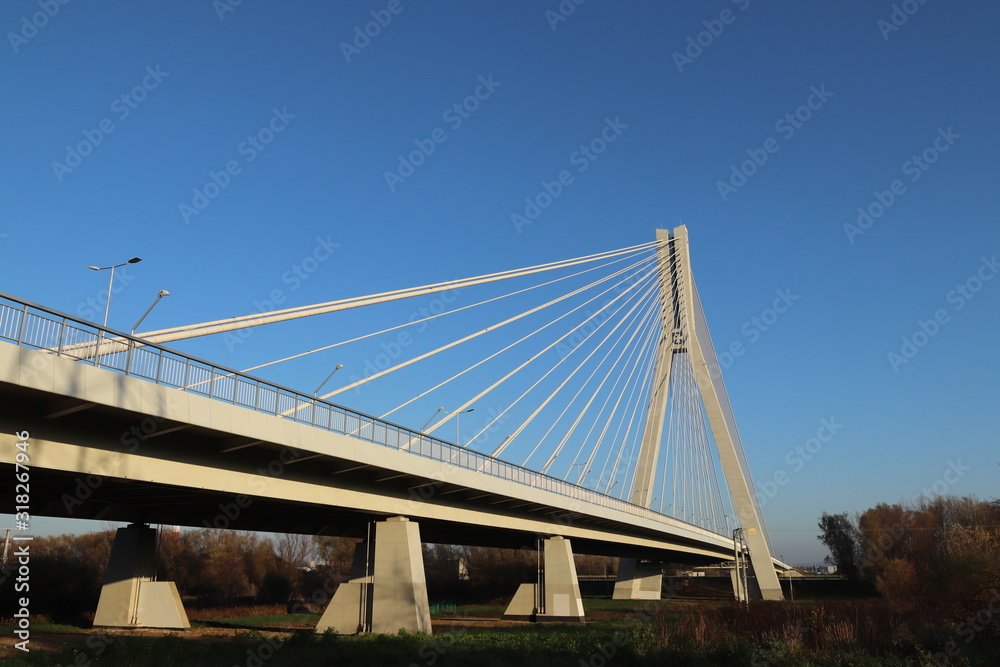 Rzeszow, Poland - 9 9 2018: Suspended road bridge across the Wislok River. Metal construction technological structure. Modern architecture. A white cross on a blue background is a symbol of the city Rzeszow, Poland - 9 9 2018: Suspended road bridge across the Wislok River. Metal construction technological structure. Modern architecture. A white cross on a blue background is a symbol of the city