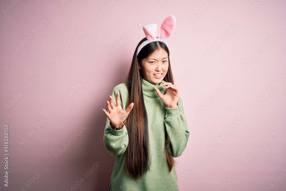 Young asian woman wearing cute easter bunny ears over pink background disgusted expression, displeased and fearful doing disgust face because aversion reaction. With hands raised Young asian woman wearing cute easter bunny ears over pink background disgusted expression, displeased and fearful doing disgust face because aversion reaction. With hands raised