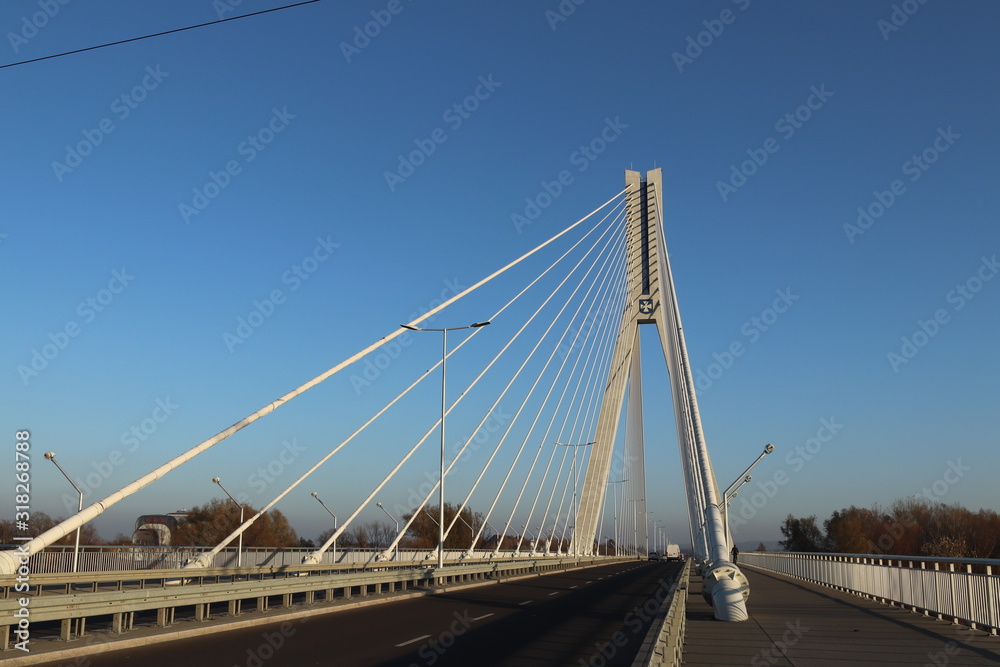 Rzeszow, Poland - 9 9 2018: Suspended road bridge across the Wislok River. Metal construction technological structure. Modern architecture. A white cross on a blue background is a symbol of the city Rzeszow, Poland - 9 9 2018: Suspended road bridge across the Wislok River. Metal construction technological structure. Modern architecture. A white cross on a blue background is a symbol of the city