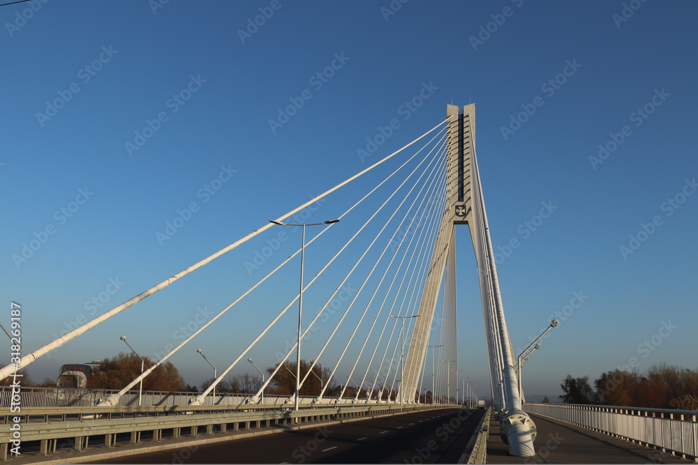 Rzeszow, Poland - 9 9 2018: Suspended road bridge across the Wislok River. Metal construction technological structure. Modern architecture. A white cross on a blue background is a symbol of the city Rzeszow, Poland - 9 9 2018: Suspended road bridge across the Wislok River. Metal construction technological structure. Modern architecture. A white cross on a blue background is a symbol of the city