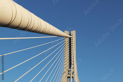 Rzeszow, Poland - 9 9 2018: Suspended road bridge across the Wislok River. Metal construction technological structure. Modern architecture. A white cross on a blue background is a symbol of the city