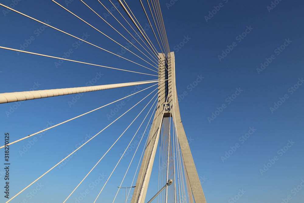 Rzeszow, Poland - 9 9 2018: Suspended road bridge across the Wislok River. Metal construction technological structure. Modern architecture. A white cross on a blue background is a symbol of the city Rzeszow, Poland - 9 9 2018: Suspended road bridge across the Wislok River. Metal construction technological structure. Modern architecture. A white cross on a blue background is a symbol of the city