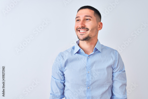 Young handsome business man standing over isolated background looking away to side with smile on face, natural expression. Laughing confident. © Krakenimages.com