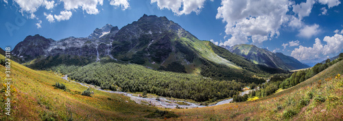 Valley in the Caucasus Mountains, green slopes and blue sky, panorama nature. Travel and vacation in the mountains.
