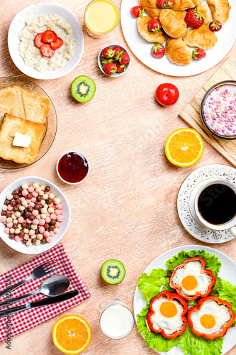 Continental breakfast with cereal  fried eggs  croissants  fruits and drinks on textured table  copy space. Table top with various healthy snacks and foods on rustic background
