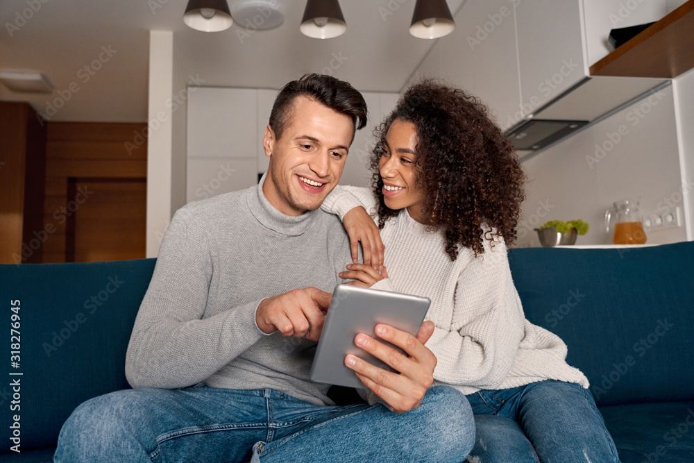 Romantic Date. Young multiethnic couple at home sitting on sofa browsing digital tablet together smiling cheerful Romantic Date. Young multiethnic couple at home sitting on sofa browsing digital tablet together smiling cheerful
