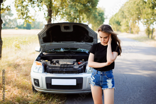 Car broke in trip. Depressed girl waiting for emergency help doesn't know what to do with broken car © Vitalii