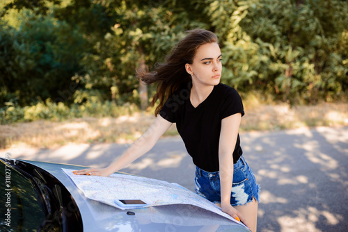 Young woman Has lost her way on the highway. Young driver has no GPS and uses paper map to find way to the destination © Vitalii