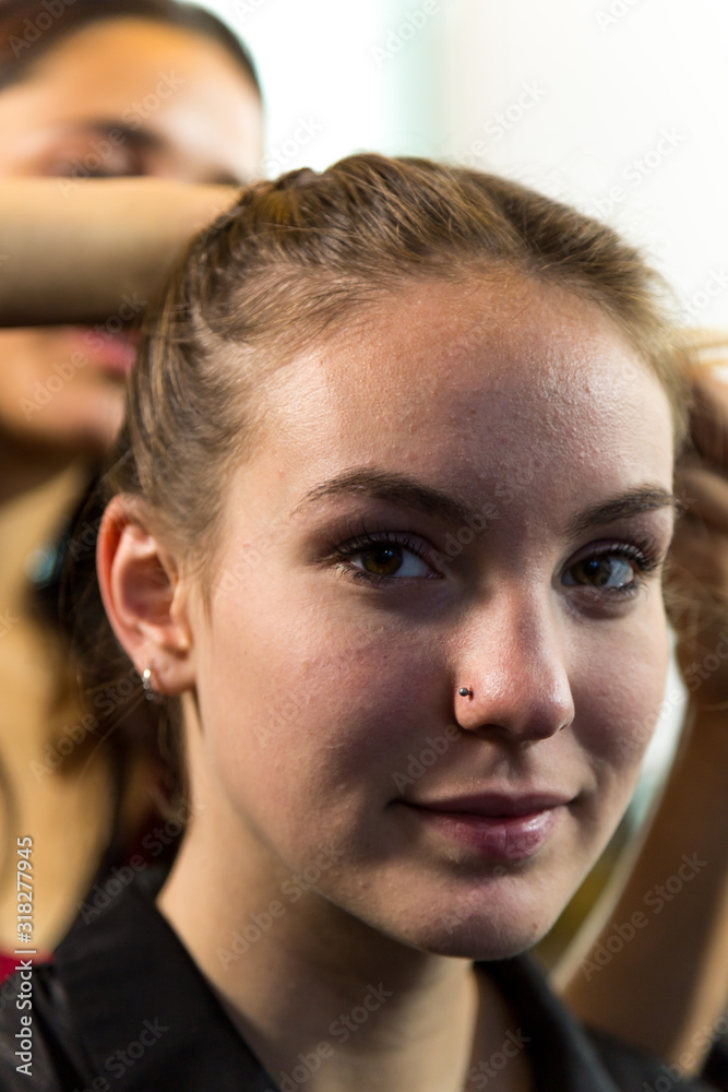 Fototapeta premium Face of Young Woman Looking at Camera while Having Hair Braided