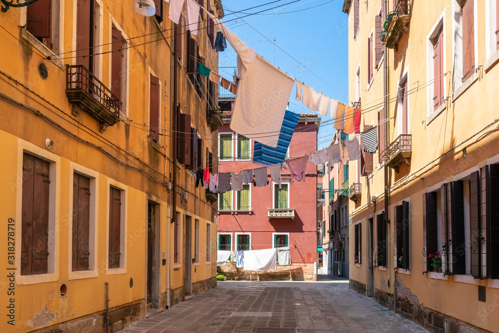 Venice. Colorful laundry is dried on the clotheslines between the houses. Authentic Venetian street in sunshine. Ancient Italian city. Lifestyle of people. Travel Tourism in Europe.