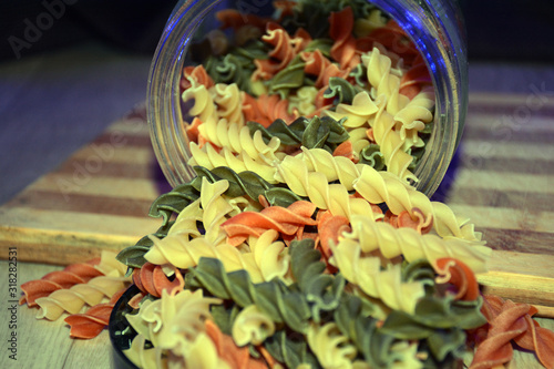 Multi-colored pasta on a wooden board. Food.