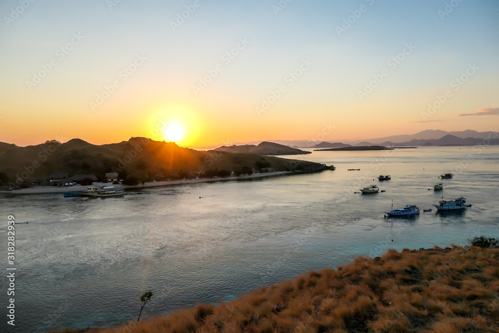 Fototapeta premium A view on a the morning sun rising over an island formation in Komodo National Park, Flores, Indonesia. Golden hour over the islands and sea. Idyllic landscape. New day beginning. Chocolate hills.