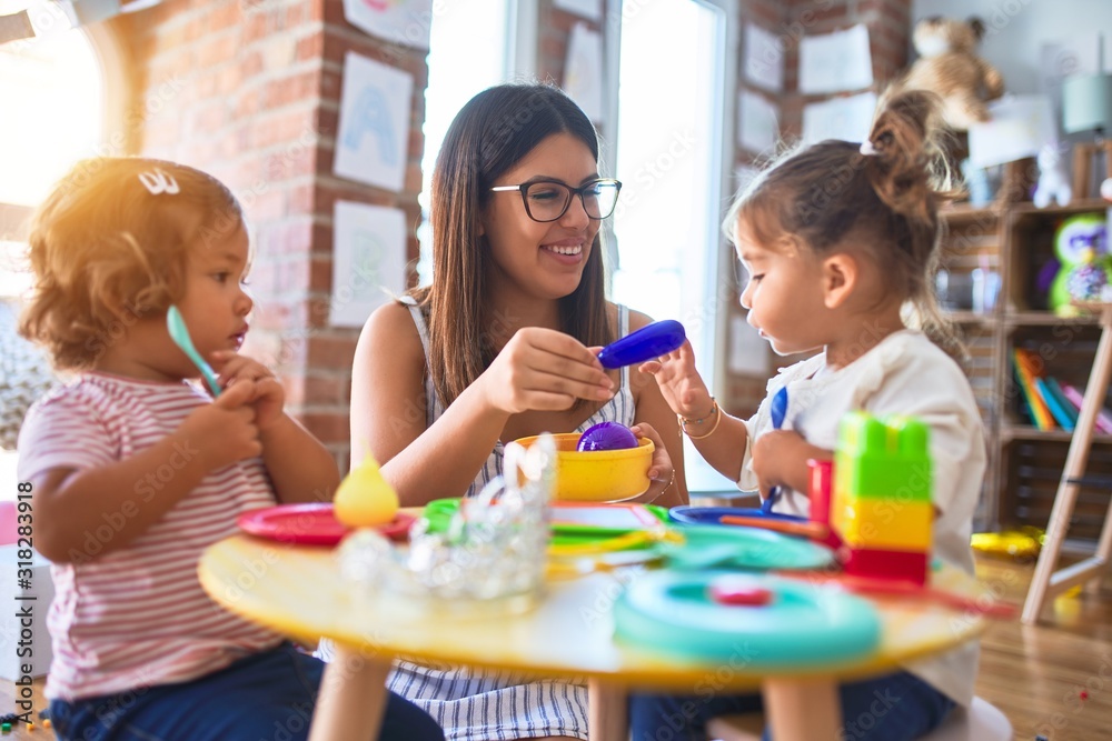 Young beautiful teacher and toddlers playing meals using plastic food and cutlery toy at kindergarten Young beautiful teacher and toddlers playing meals using plastic food and cutlery toy at kindergarten
