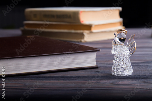 Glass angel and books. Close-up. Holy books concept.