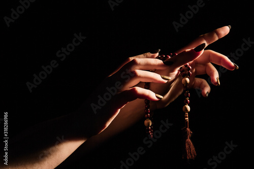 Rosary And Cross In Female Hands On A Dark Background. Close-up.