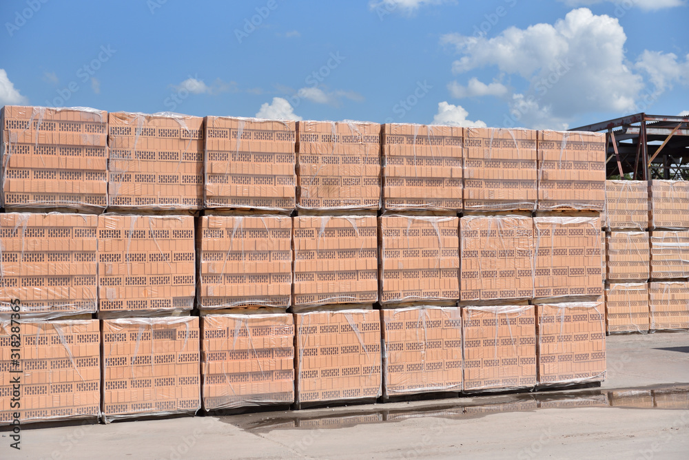Packed new bricks lies in the outdoors warehouse of the factory against the blue sky. Packed new bricks lies in the outdoors warehouse of the factory against the blue sky.