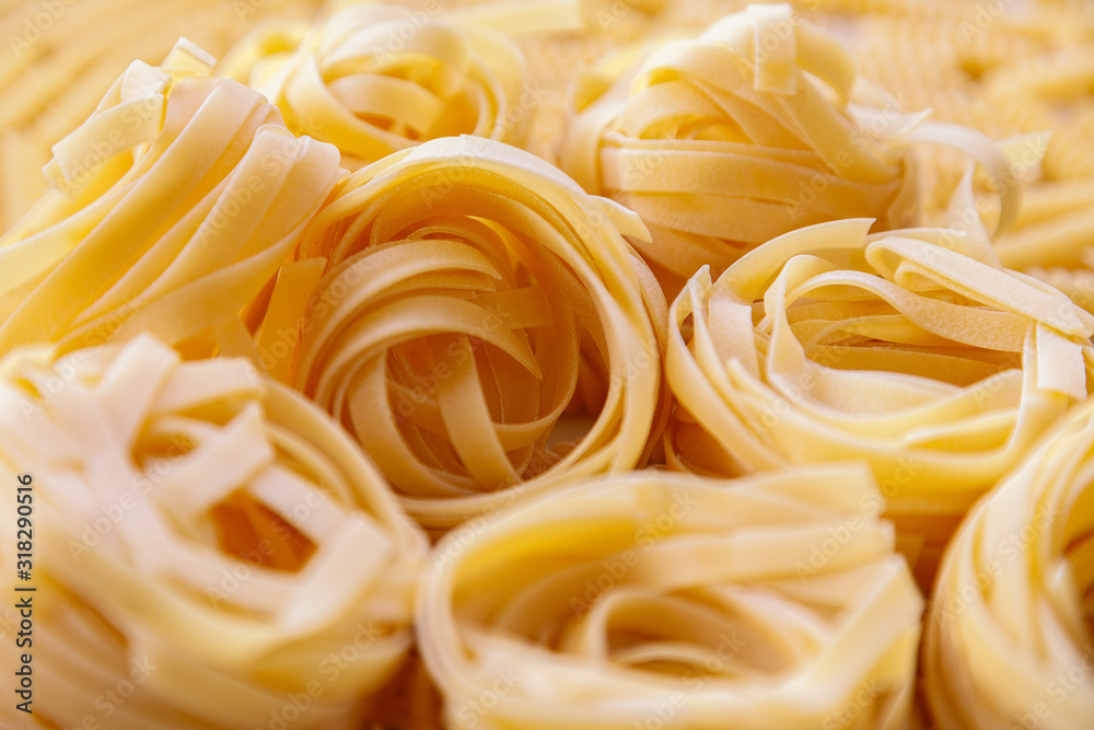 Italian homemade rolled raw fettuccine pasta background. Angle view Italian homemade rolled raw fettuccine pasta background. Angle view