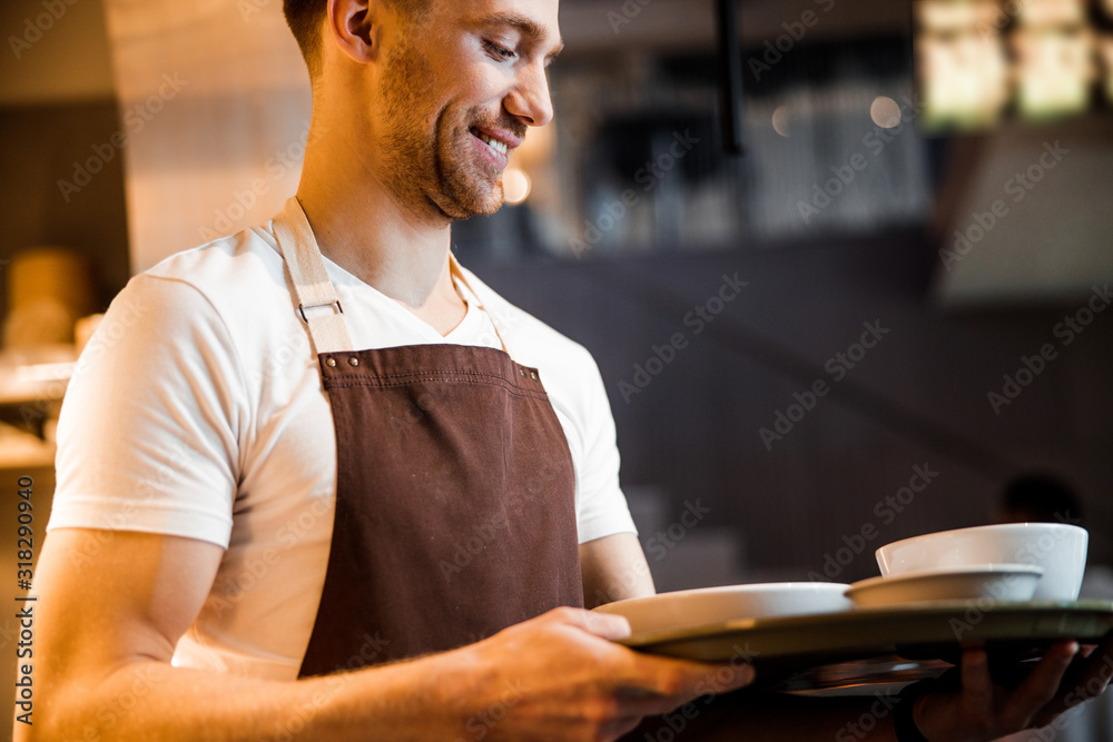 Caucasian happy waiter waiting for order near the kitchen Caucasian happy waiter waiting for order near the kitchen