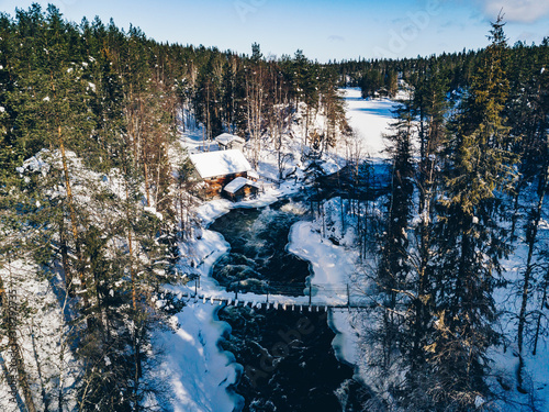 Aerial view of fast river with suspension foot bridge. Snow winter forest in Finland photo