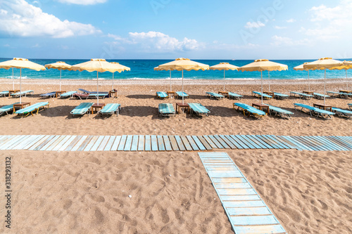 Fototapeta Naklejka Na Ścianę i Meble -  Empty sunbeds and umbrella on Afandou beach near Faliraki (Rhodes, Greece)