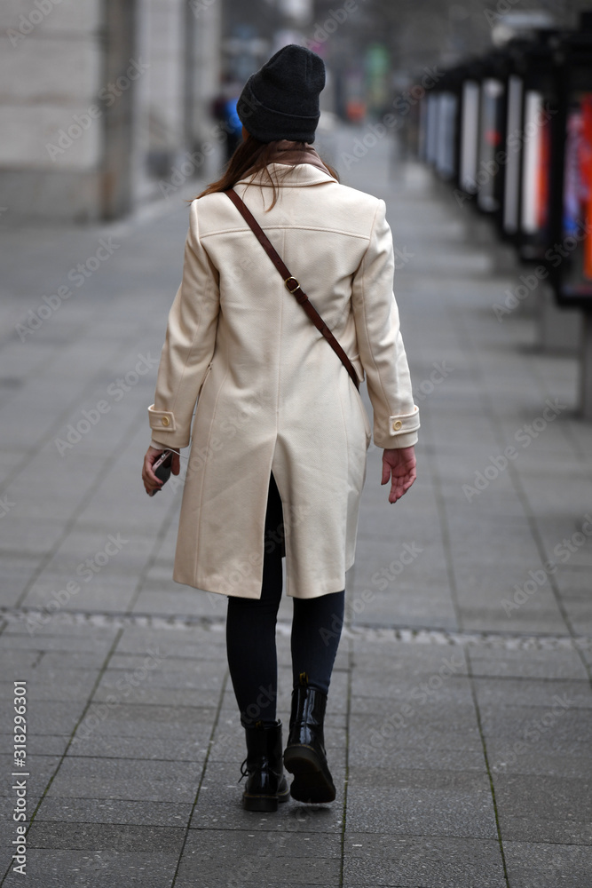 A young, stylish dressed woman walks on the Kuhdamm in Berlin-Germany on a cold winter day.